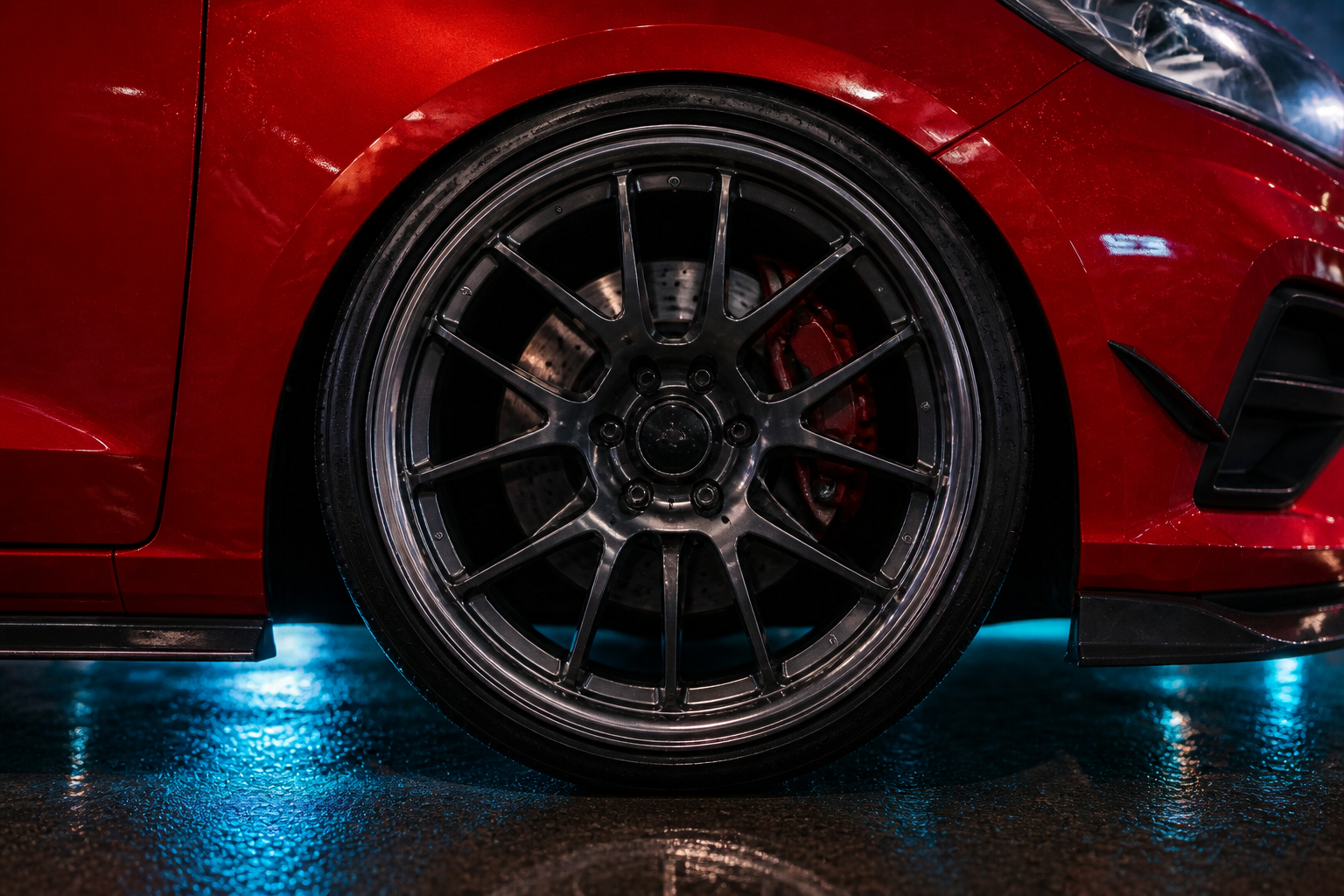 Closeup of the Bairro Rua 4 dark multi-spoke rim, drilled brake rotor and red caliper
