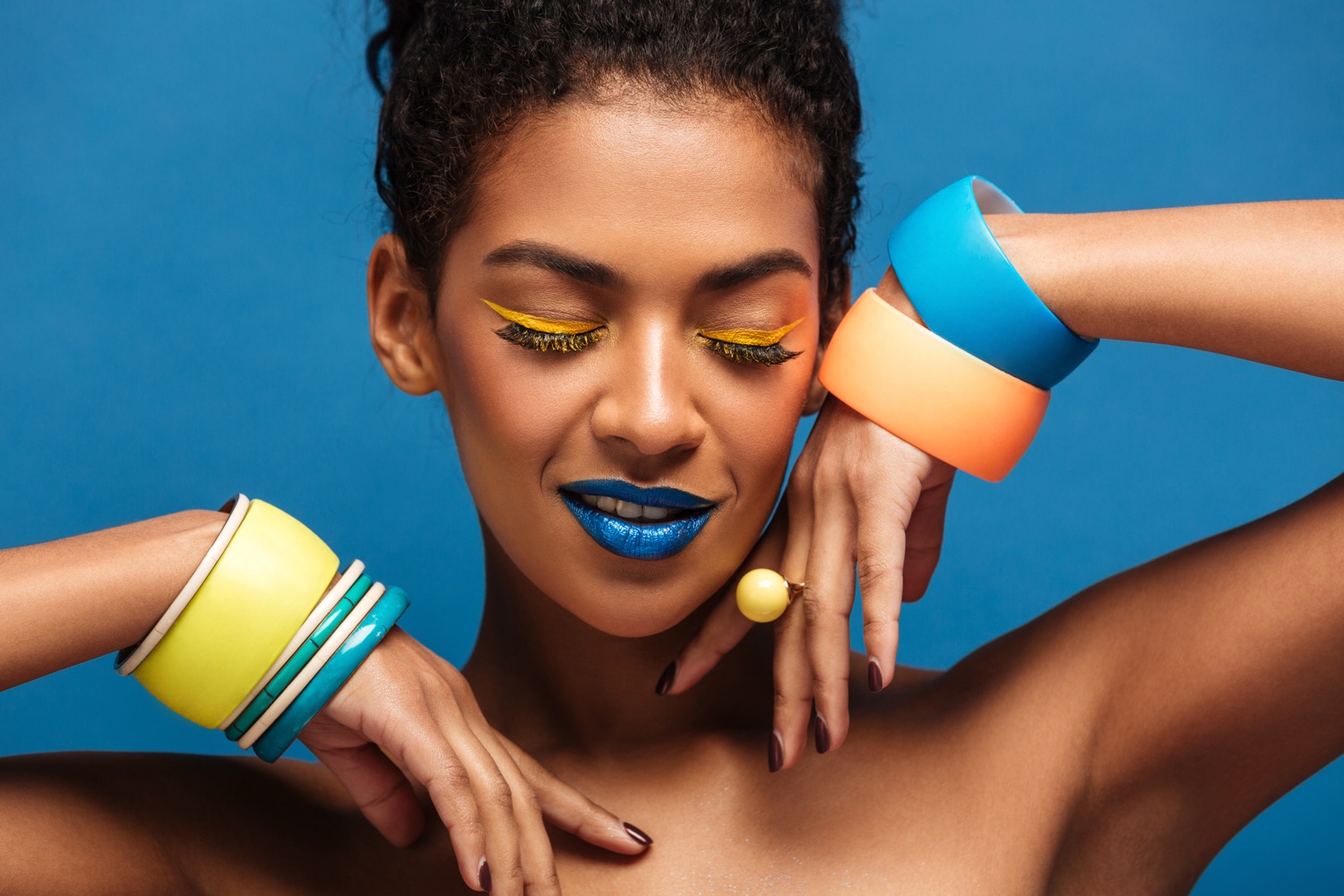 A bold 1985-style beauty portrait — saturated blue eye color, sculpted cheek and statement makeup