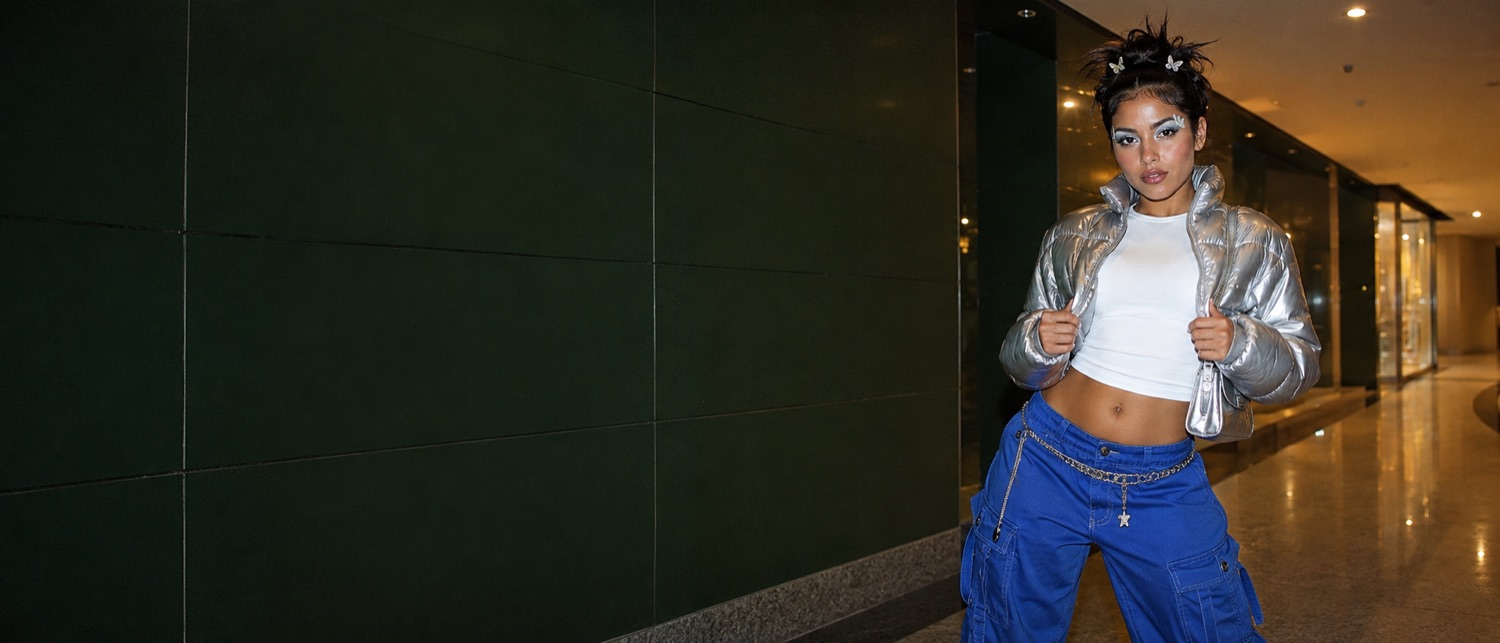 A full Y2K look: silver puffer jacket, white baby tee and cobalt low-rise cargos with a chain belt