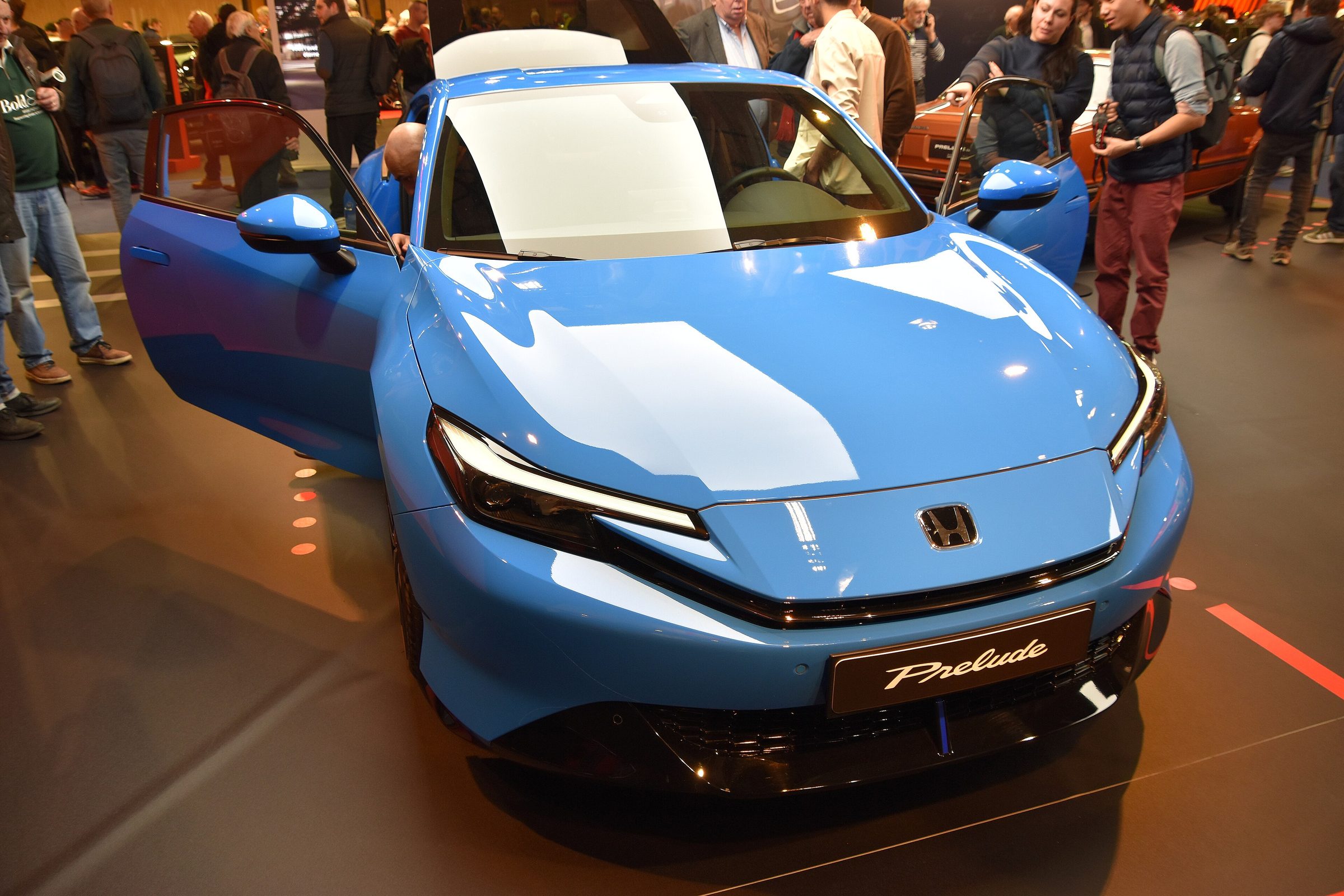 2026 Honda Prelude in blue, front three-quarter view with the door open at a show.