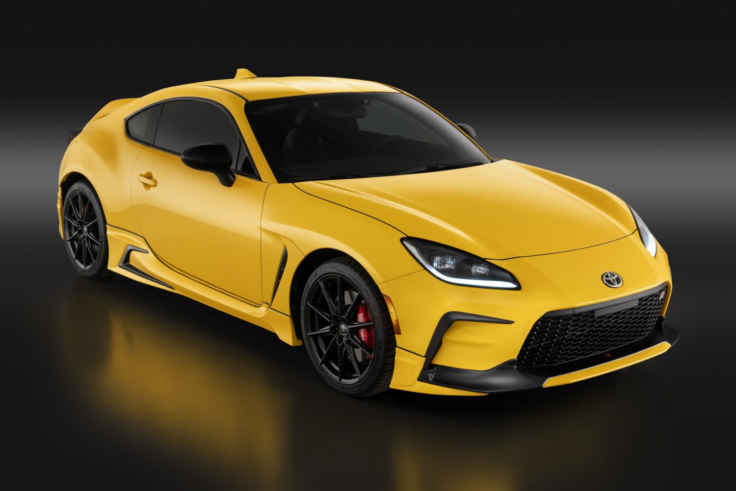2026 Toyota GR86 Yuzu Edition in bright yellow, studio front three-quarter view.