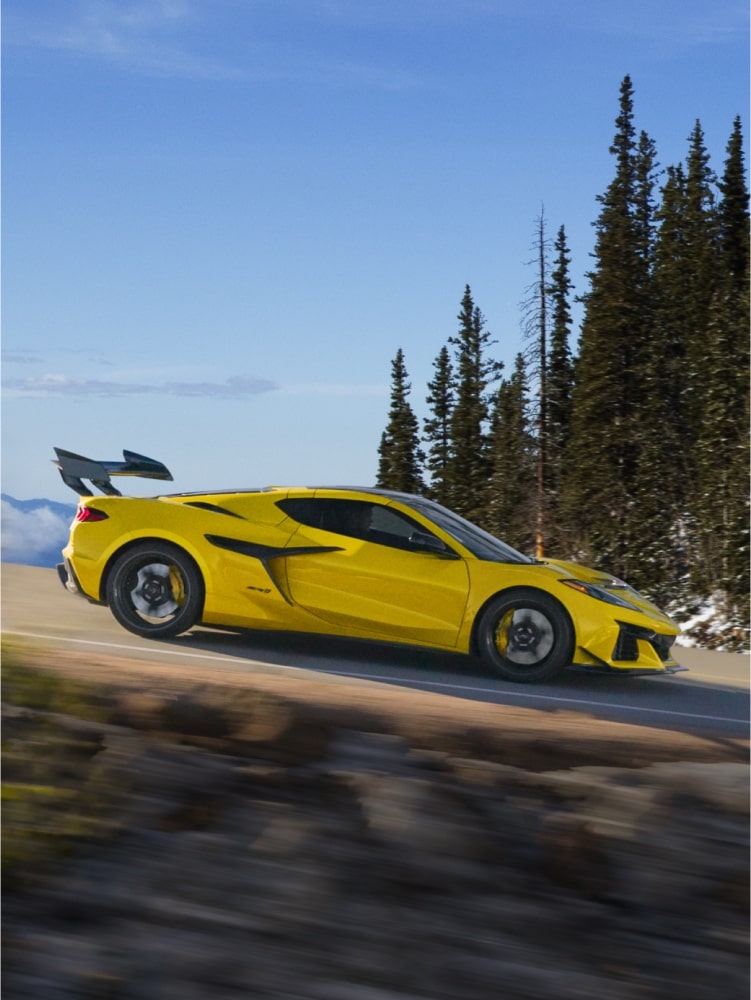 2027 Chevrolet Corvette ZR1 in yellow, cornering on a mountain road.