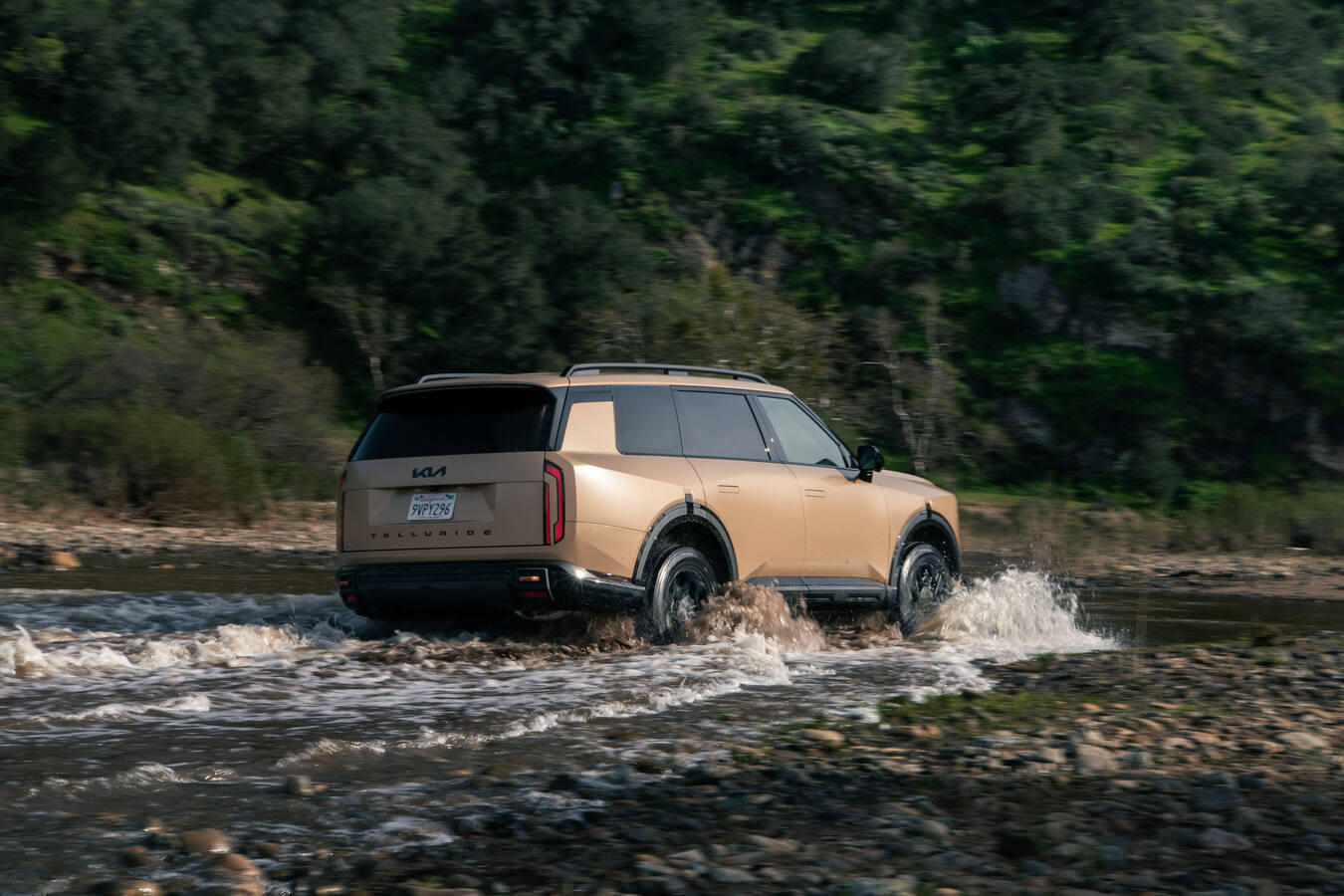 2027 Kia Telluride X-Pro parked on rocky terrain in a grassy field, official Kia press photography.