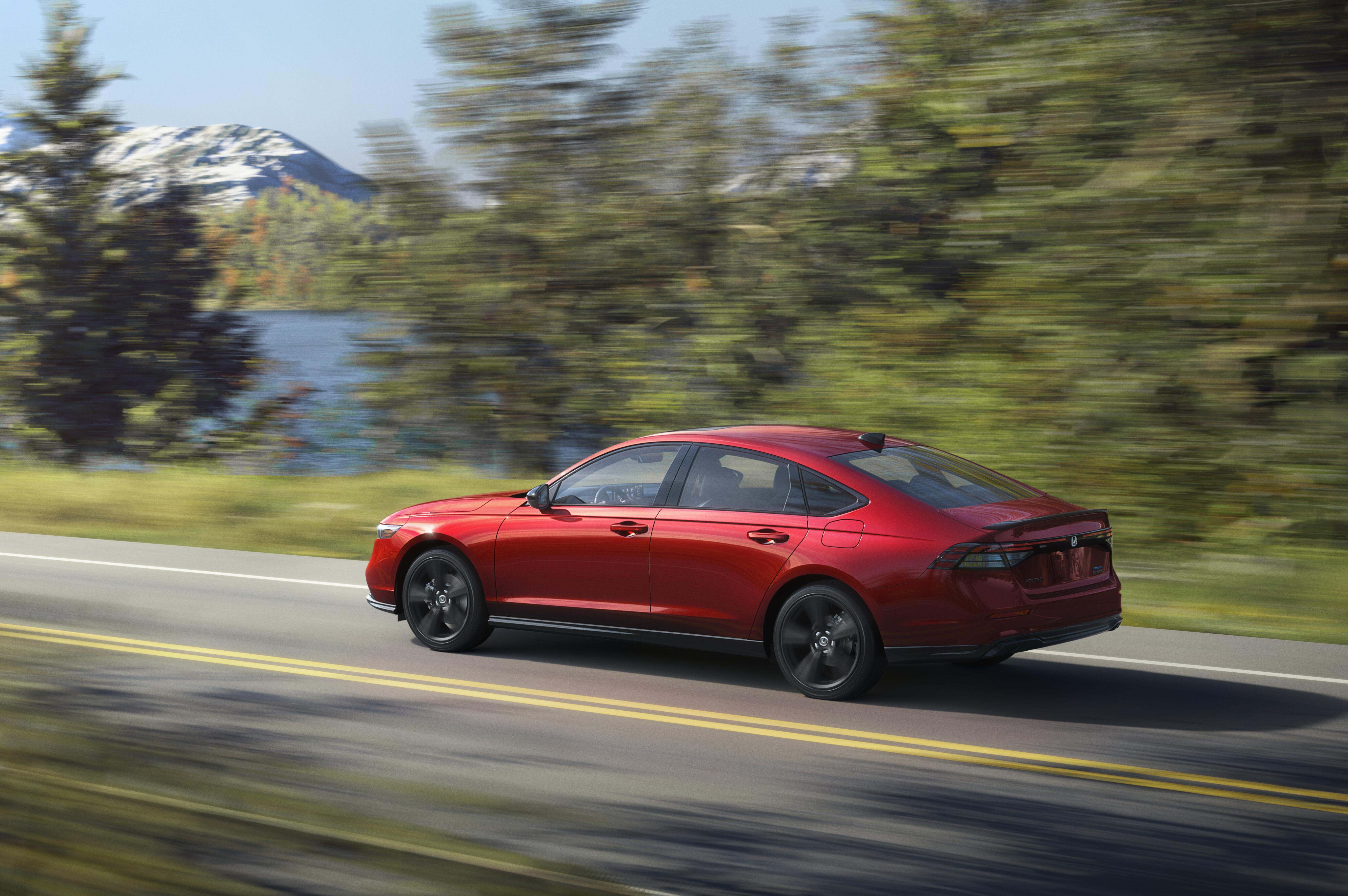 2027 Honda Accord Sport-L Hybrid in black, rear three-quarter in motion, official Honda press photograph.