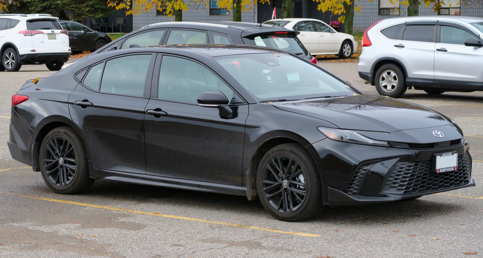 2027 Toyota Camry Hybrid SE Upgrade AWD in Midnight Black Metallic, front three-quarter, real photograph.