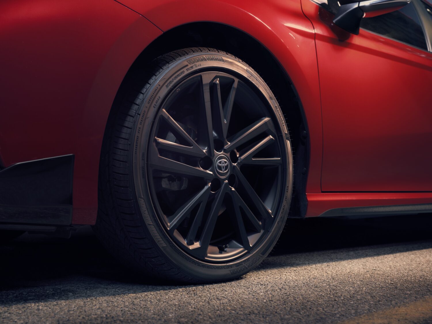 2027 Toyota Camry Nightshade Edition, rear three-quarter in motion, official Toyota press photograph.