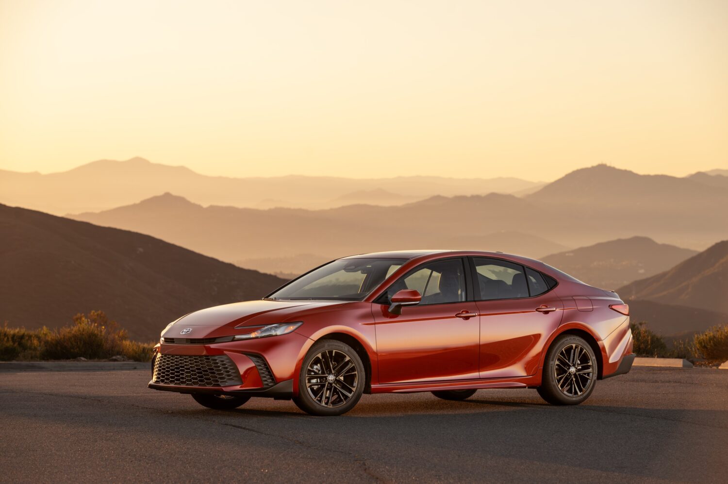 2027 Toyota Camry SE AWD in Supersonic Red, front three-quarter, official Toyota press photograph.