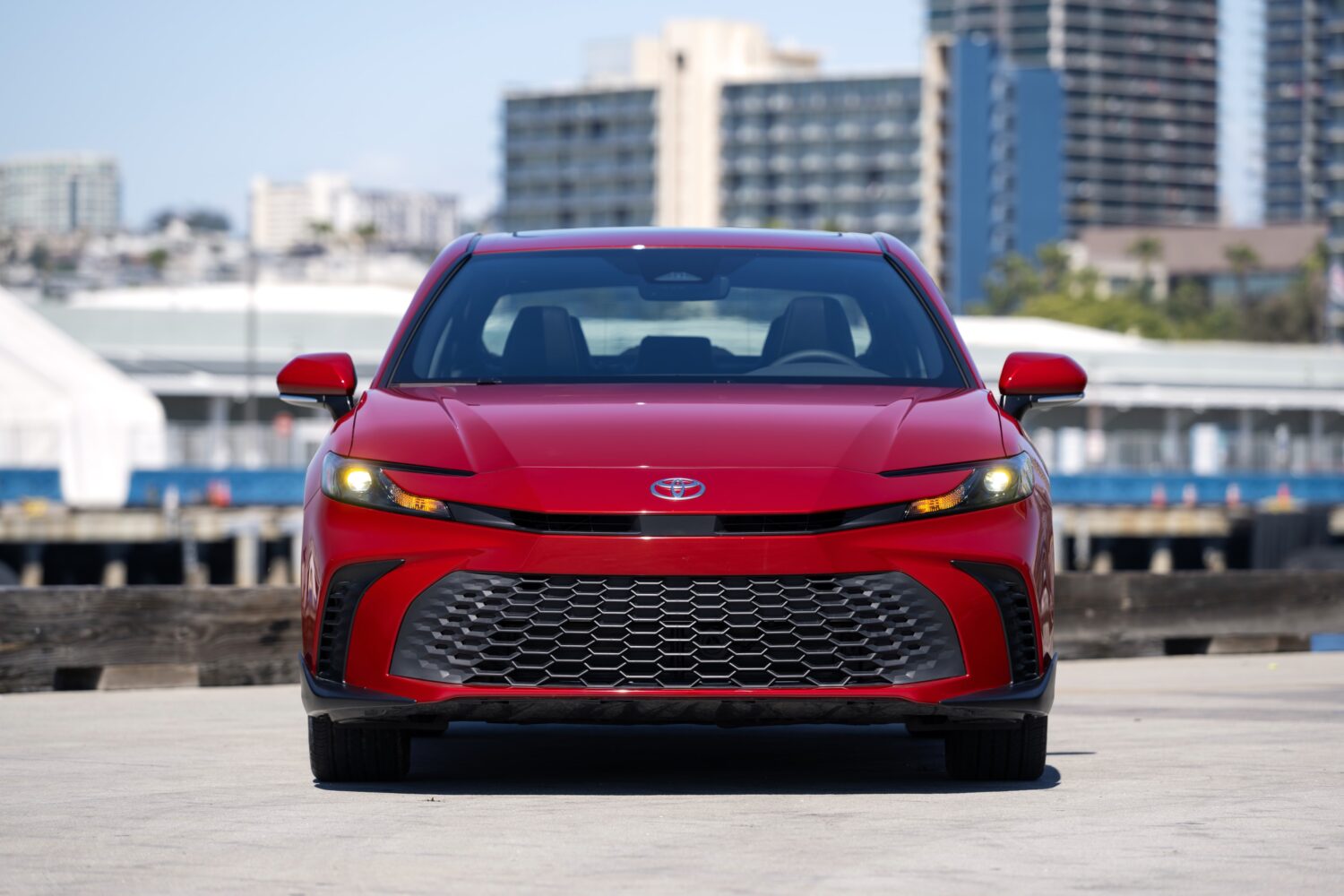 2027 Toyota Camry SE AWD in Supersonic Red, side profile, official Toyota press photograph.