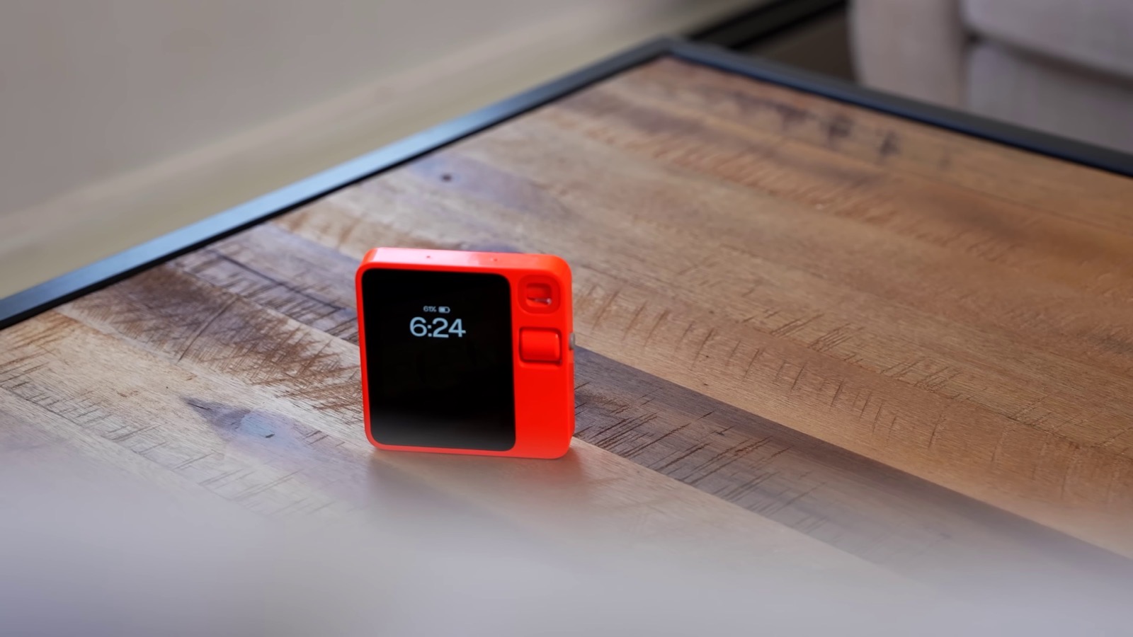 The Rabbit r1, an orange pocket AI device, resting on a wood table, a real photograph from the same 2024 wave of AI hardware as Humane's AI Pin.
