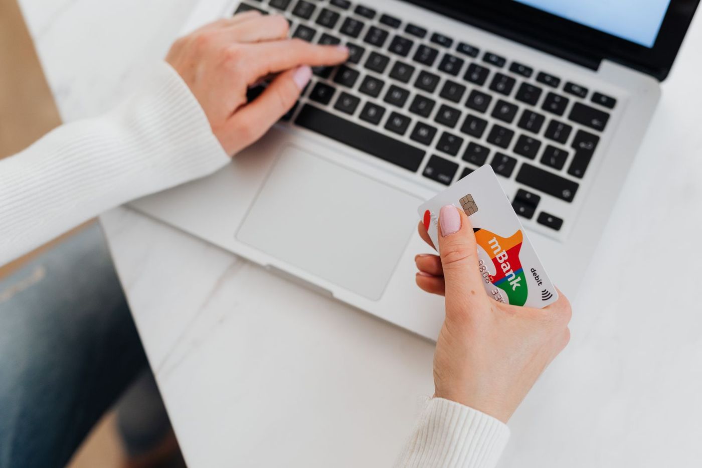 Hands holding a credit card over a laptop keyboard while shopping online