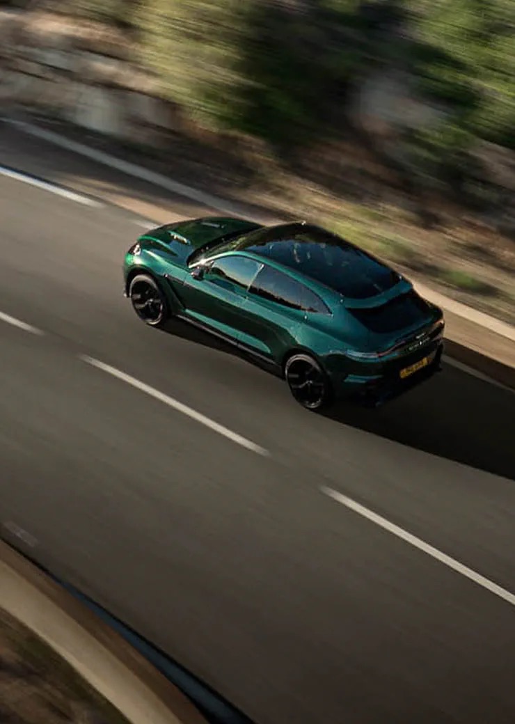 Overhead rear three-quarter view of the Aston Martin DBX707 driving on a mountain road.