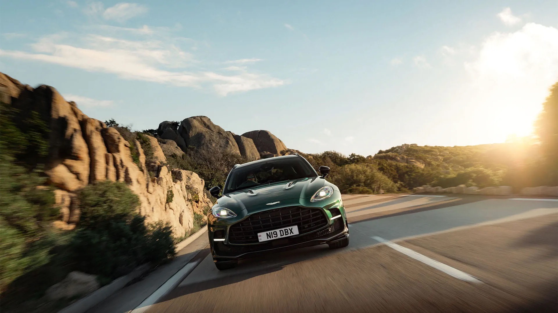Aston Martin DBX707 in green, driving on a coastal mountain road.