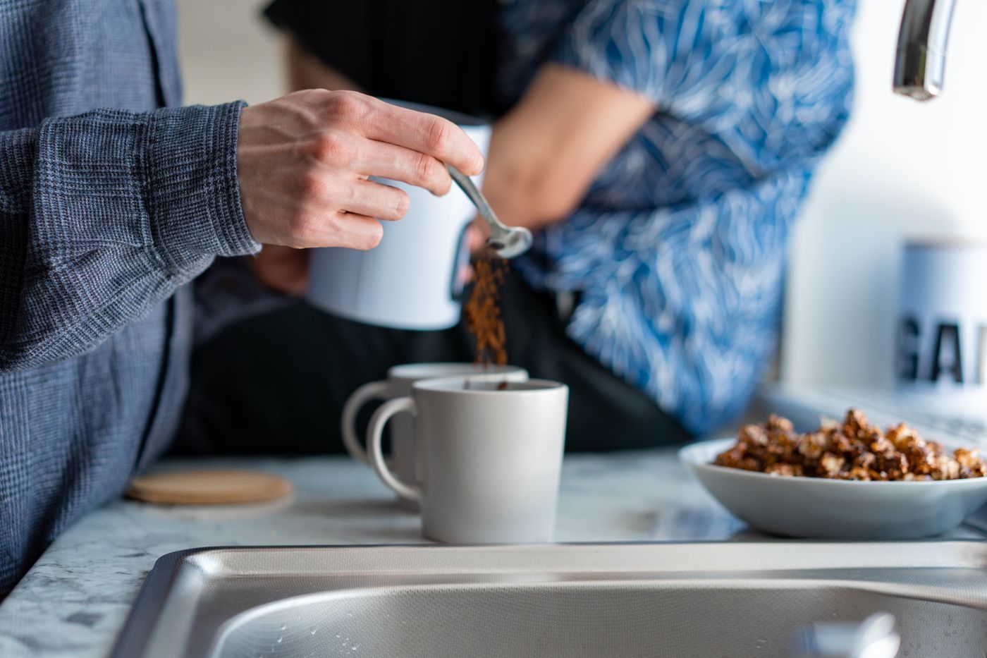 Two people making coffee in a kitchen next to a sink