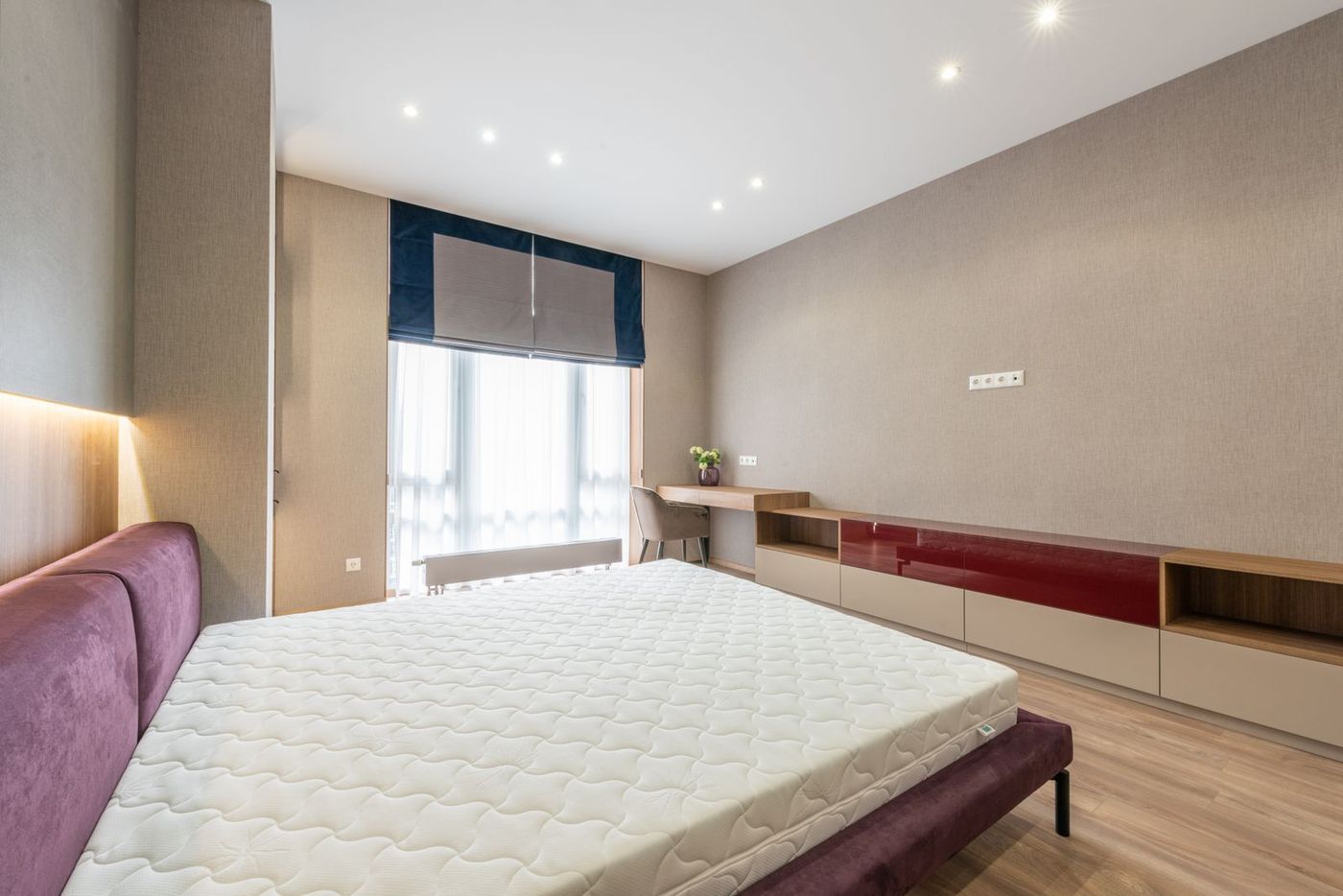 Bedroom with a white mattress on a bed frame by a window