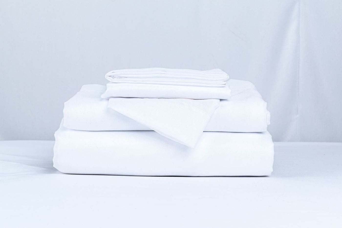 Neatly folded white bed sheets stacked together