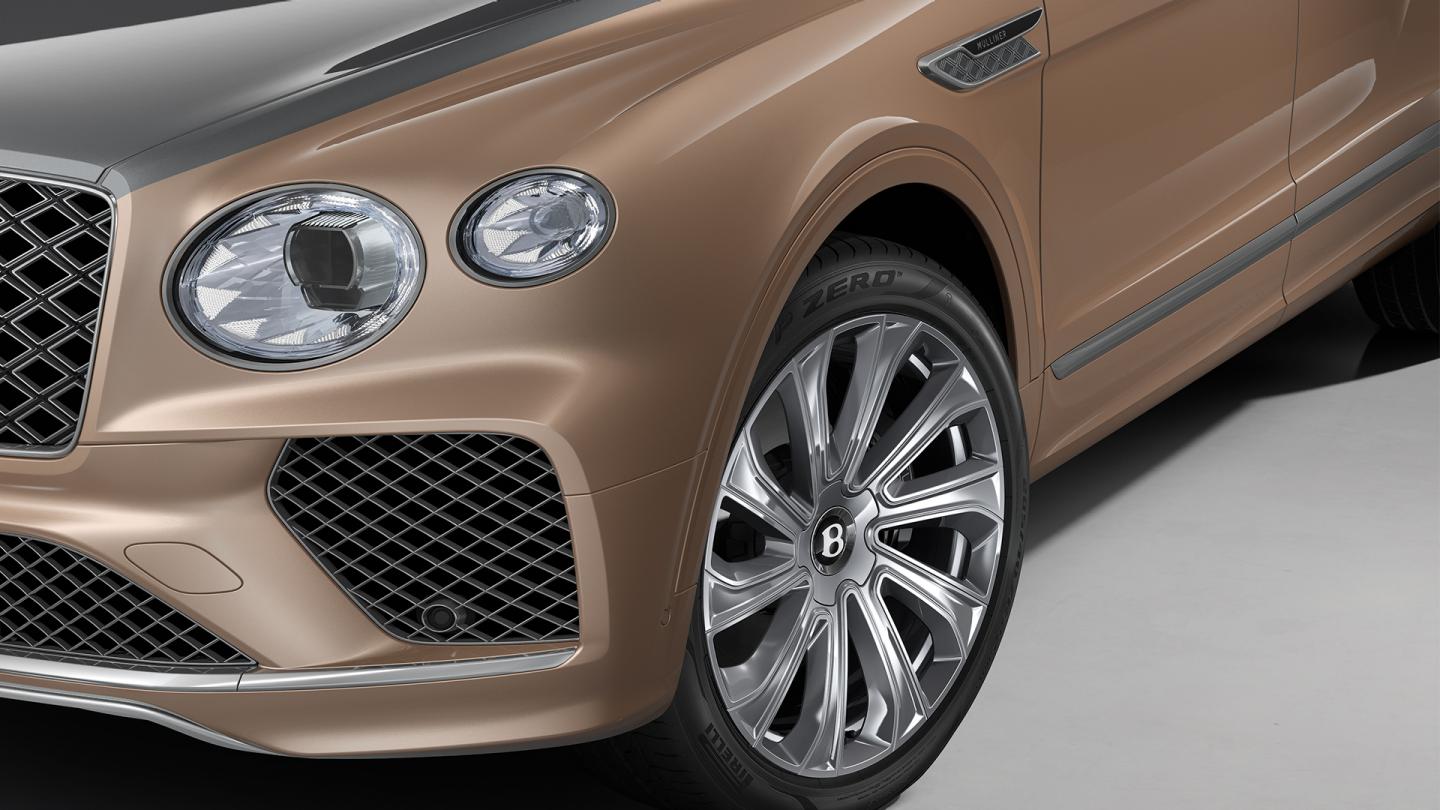 Close-up of the Bentley Bentayga EWB Mulliner's front wheel, headlight, and grille.