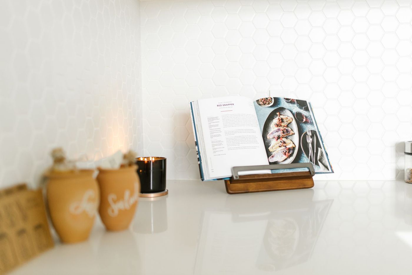 An open cookbook on a stand on a white kitchen counter