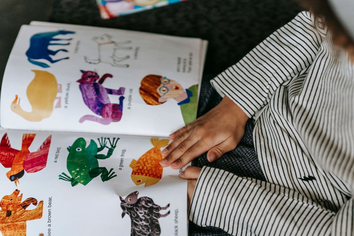 A child looking at a colorful illustrated animal picture book