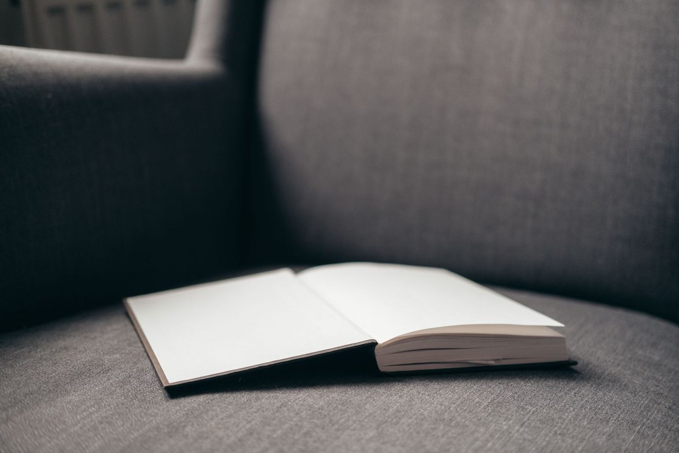 An open book resting on a gray armchair