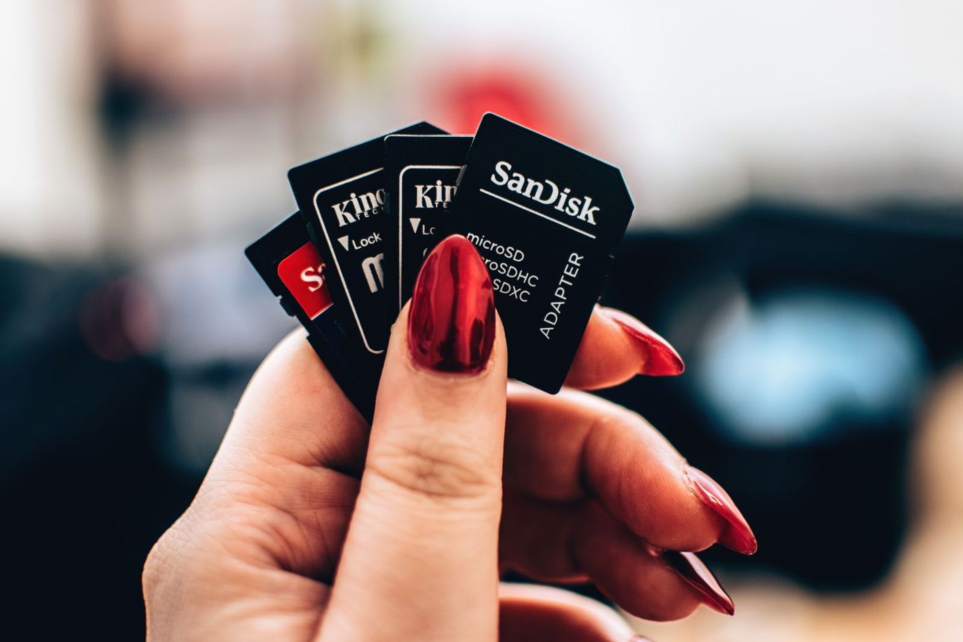 A hand holding several microSD adapters, the card format most dash cams use.