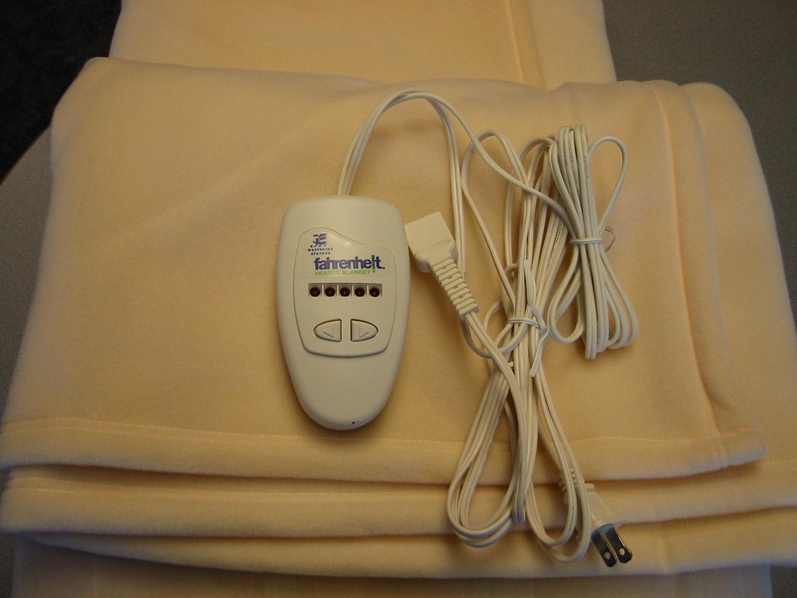 A folded heated blanket with its digital heat-setting controller and power cord laid on top, a real photograph.