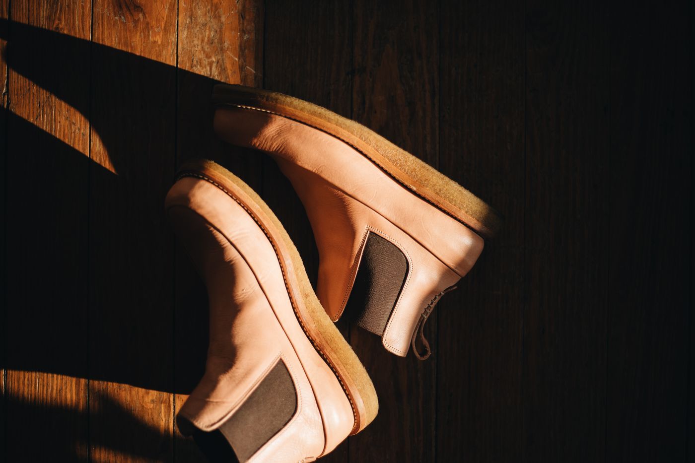 Pair of tan leather Chelsea boots on a wooden floor