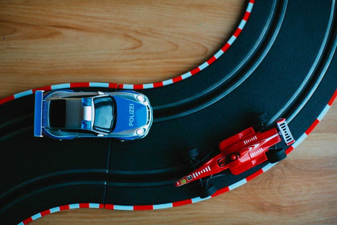 Two toy cars on a slot-car track, one blue and one red