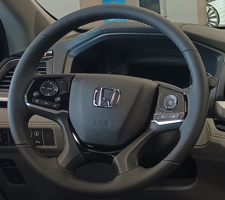 Detail crop of the Odyssey steering wheel and its physical buttons.