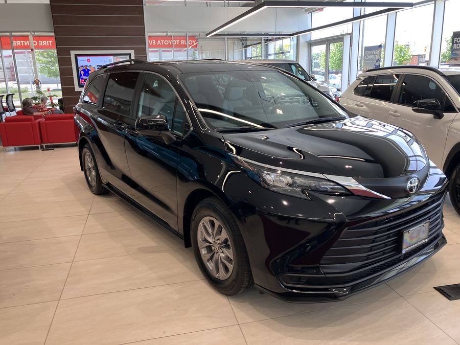 2026 Toyota Sienna in black on a showroom floor, front three-quarter view.