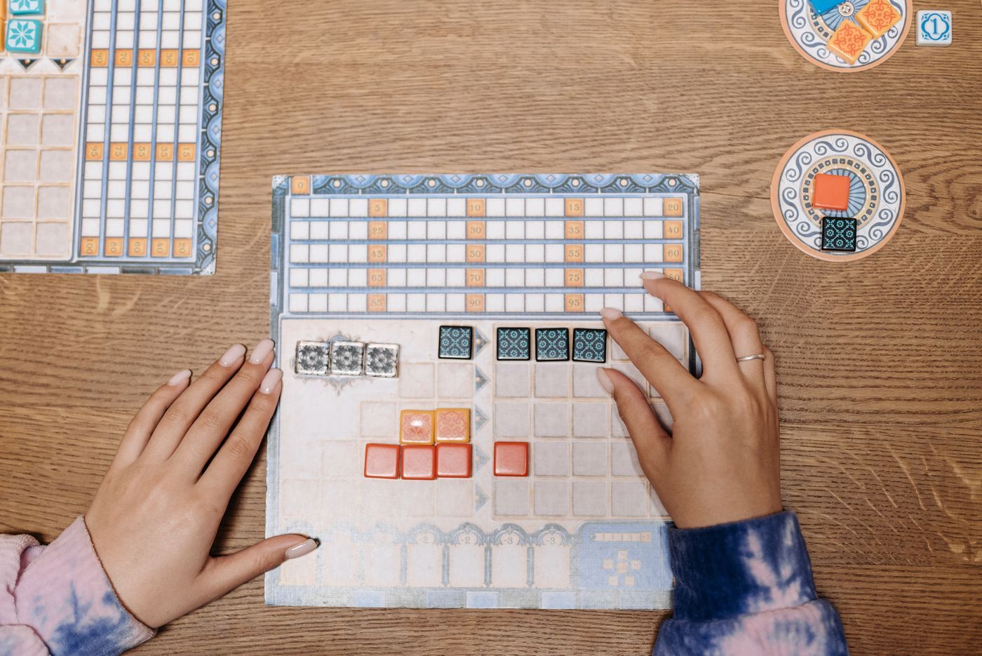 Two people's hands moving pieces on a tabletop board game