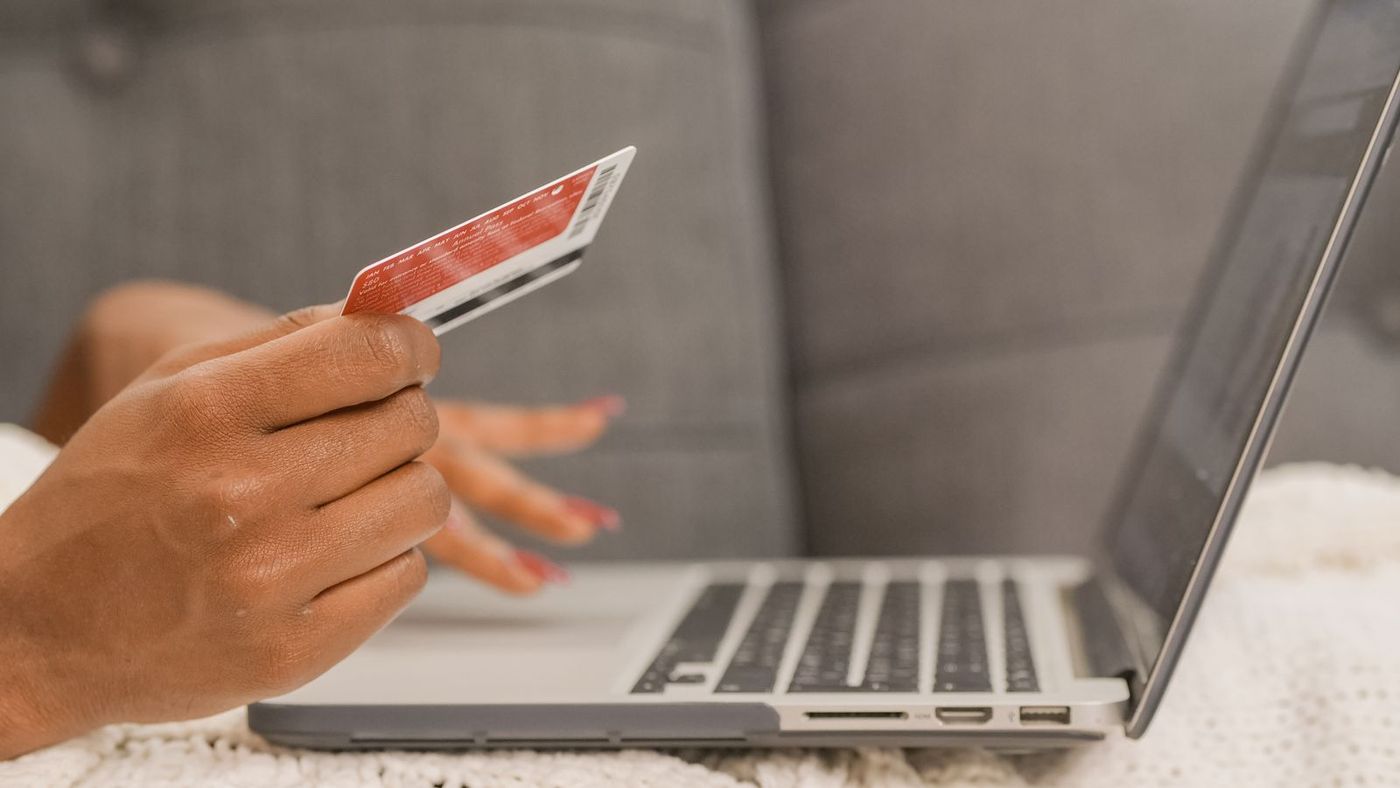 Hand holding a credit card beside an open laptop