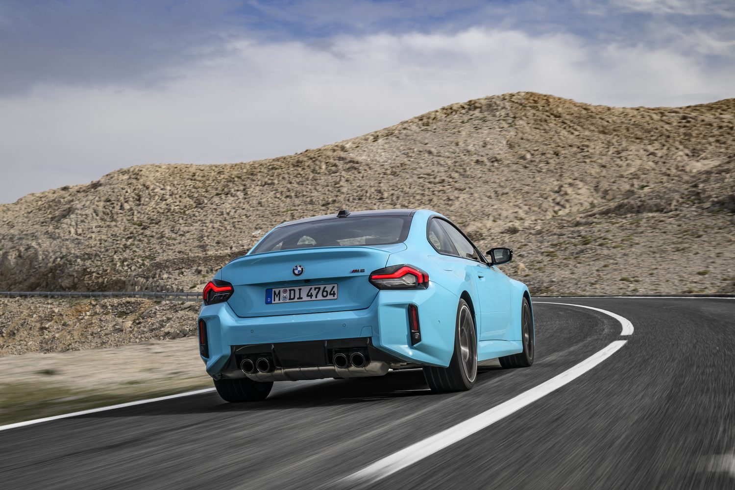 BMW M2 with M xDrive cornering on a mountain road.