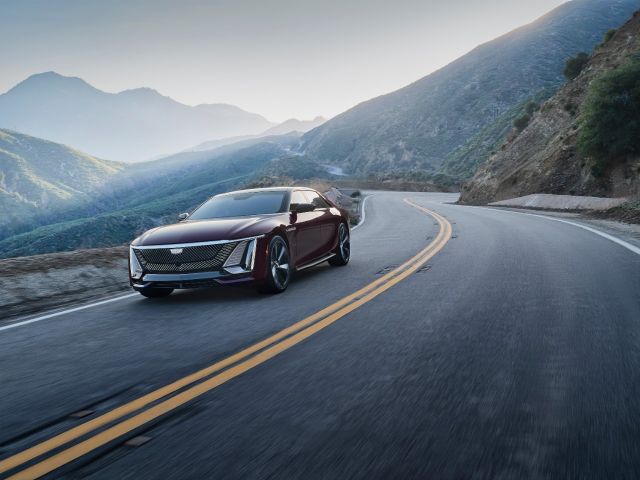 A dark red Cadillac Celestiq driving on a winding mountain road.