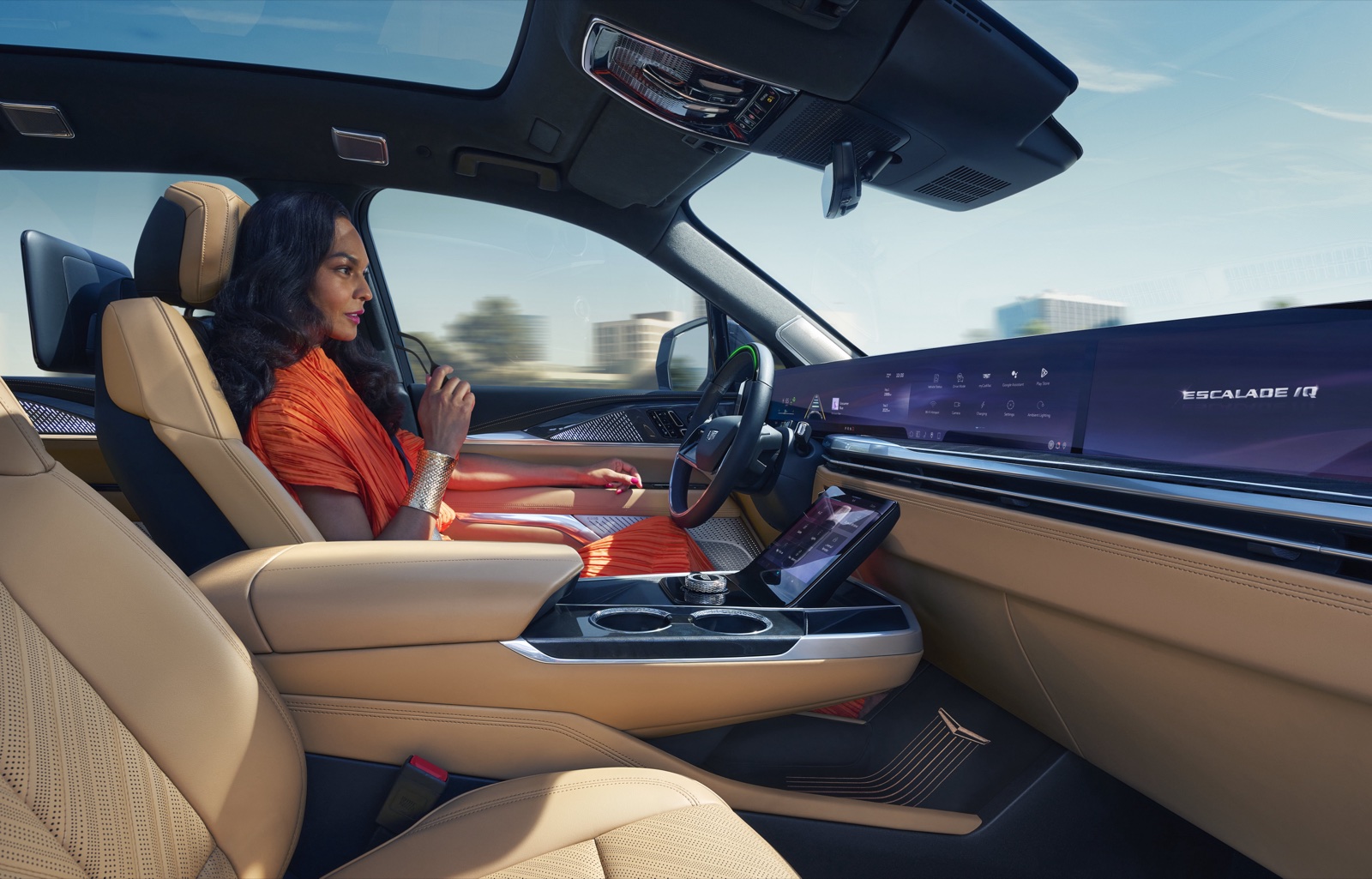 The Escalade IQ interior, showing the curved 55-inch pillar-to-pillar display and a driver with hands off the wheel.