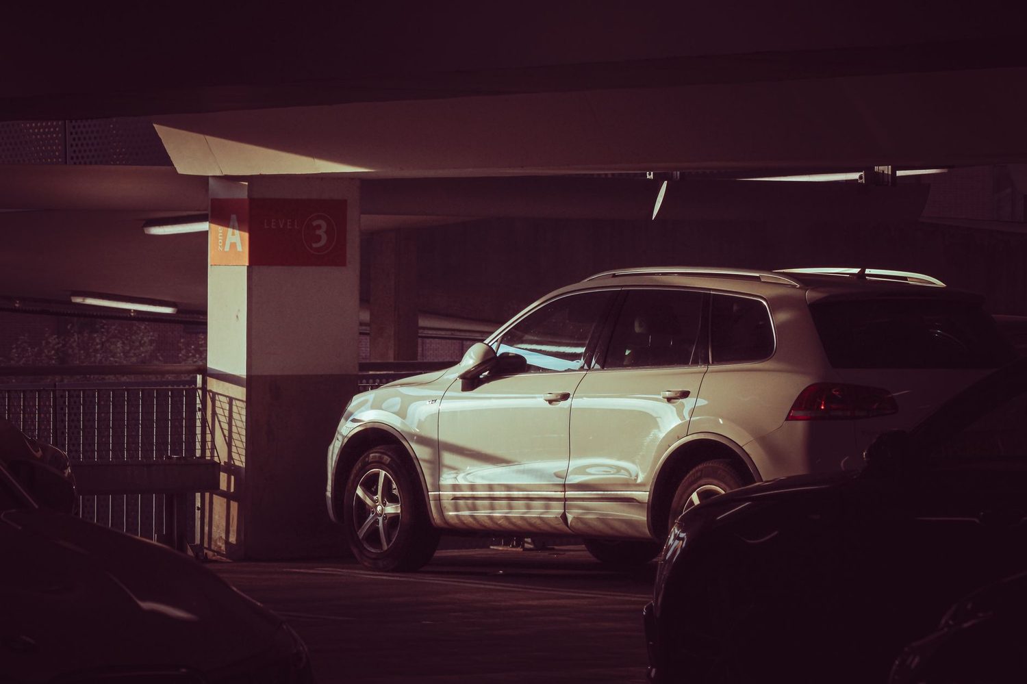 A white SUV in a parking structure, showing its height relative to the cars around it.