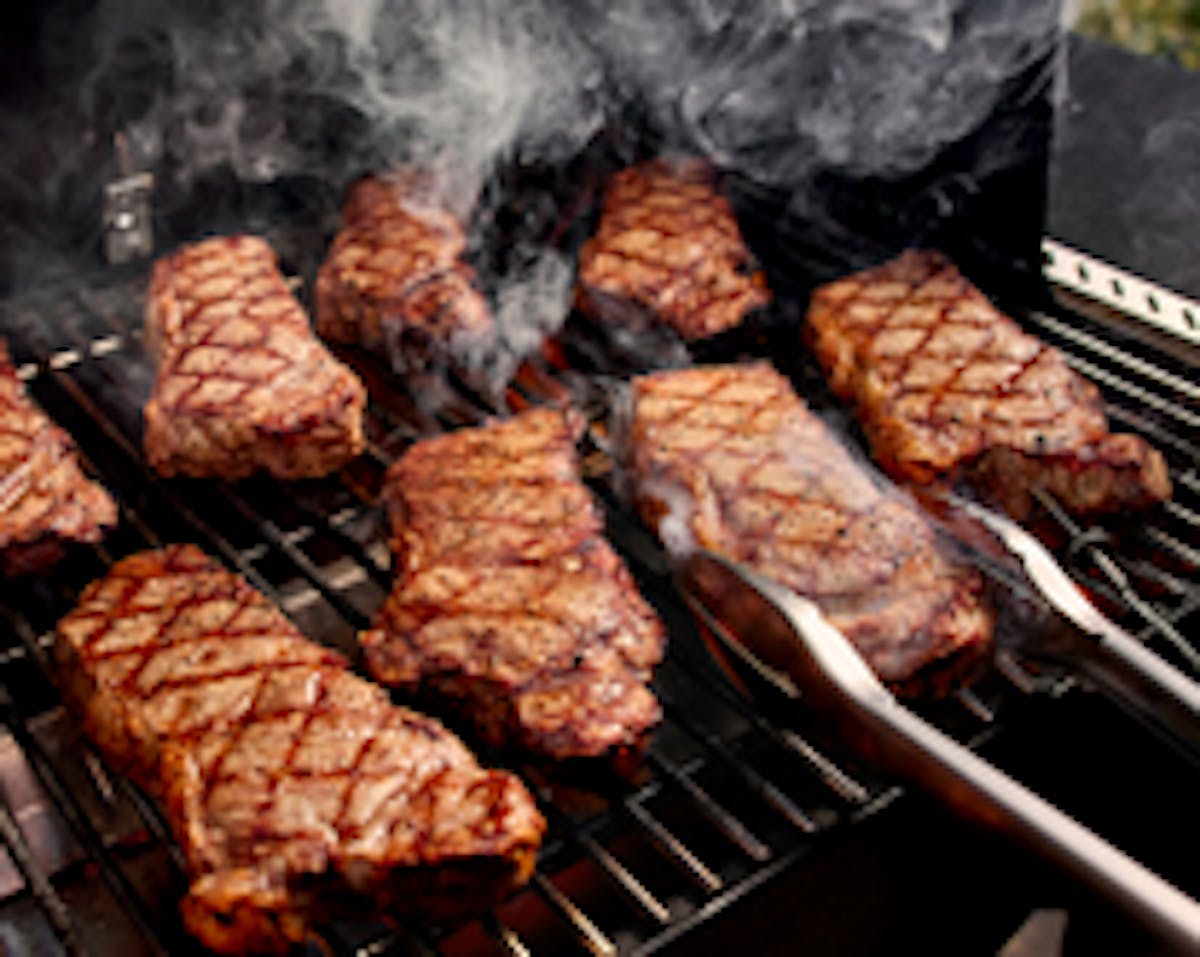 A steak being grilled with visible sear marks.