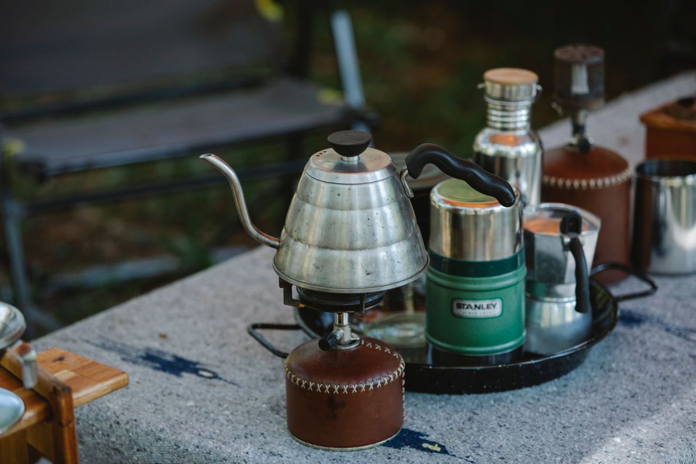 Camp stove, kettle and insulated bottle on a table