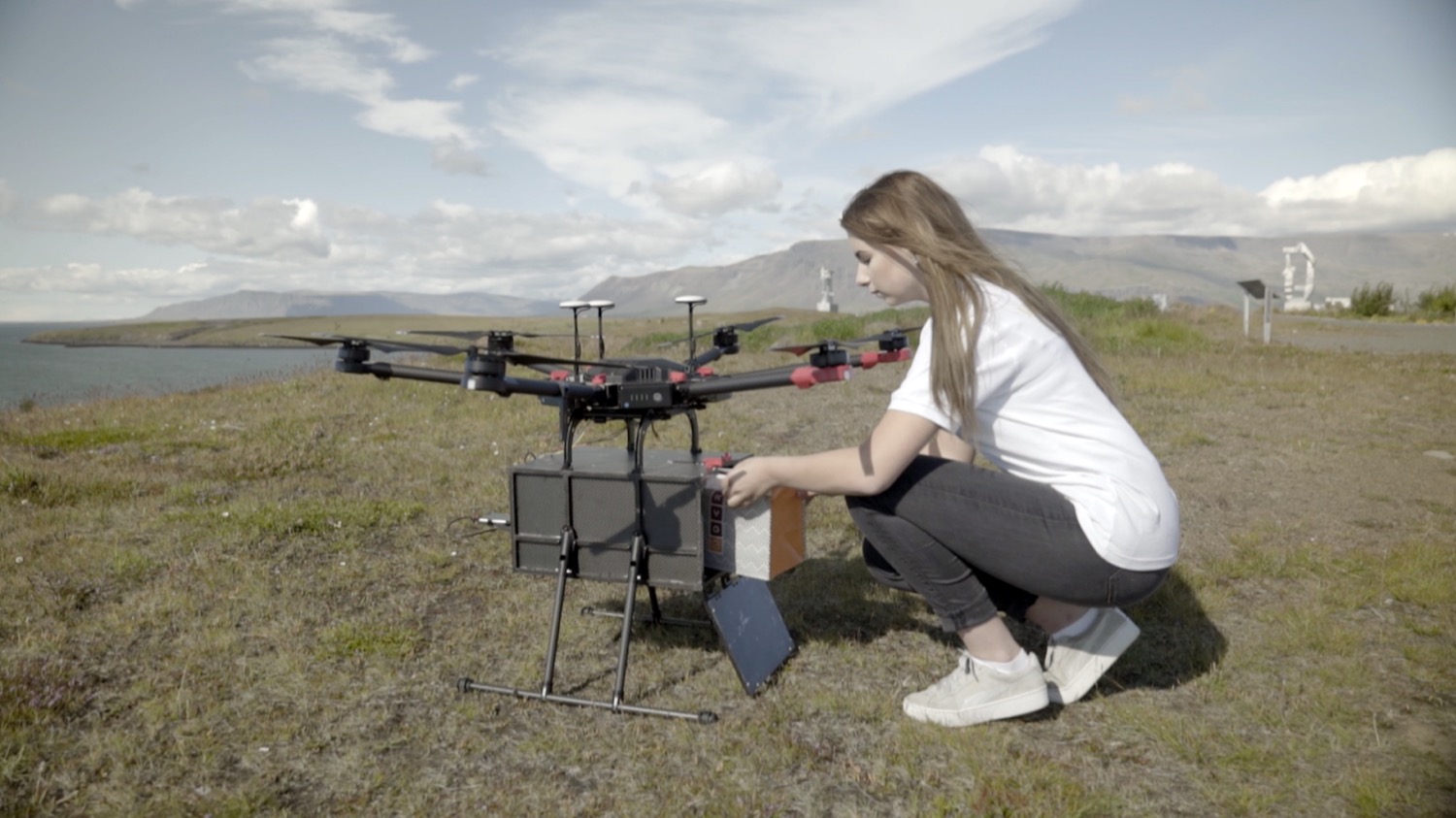 A person beside a Flytrex delivery drone in a field.