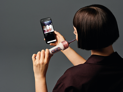 Person using the Dyson CameraJet with the companion app showing a live in-mouth camera feed, real photograph.