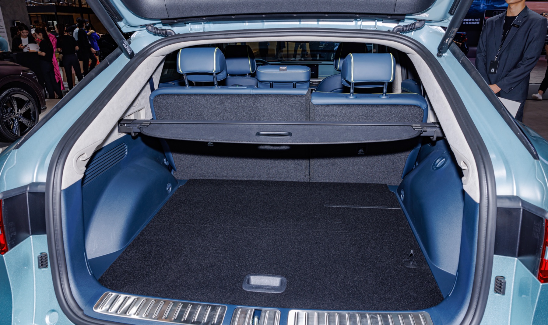 Genesis GV60 cargo area with rear seats and cargo cover visible, auto show photography.