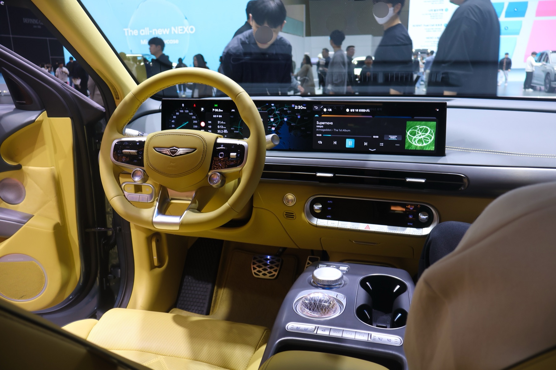 Genesis GV60 interior in yellow leather, dashboard and 27-inch display, auto show photography.