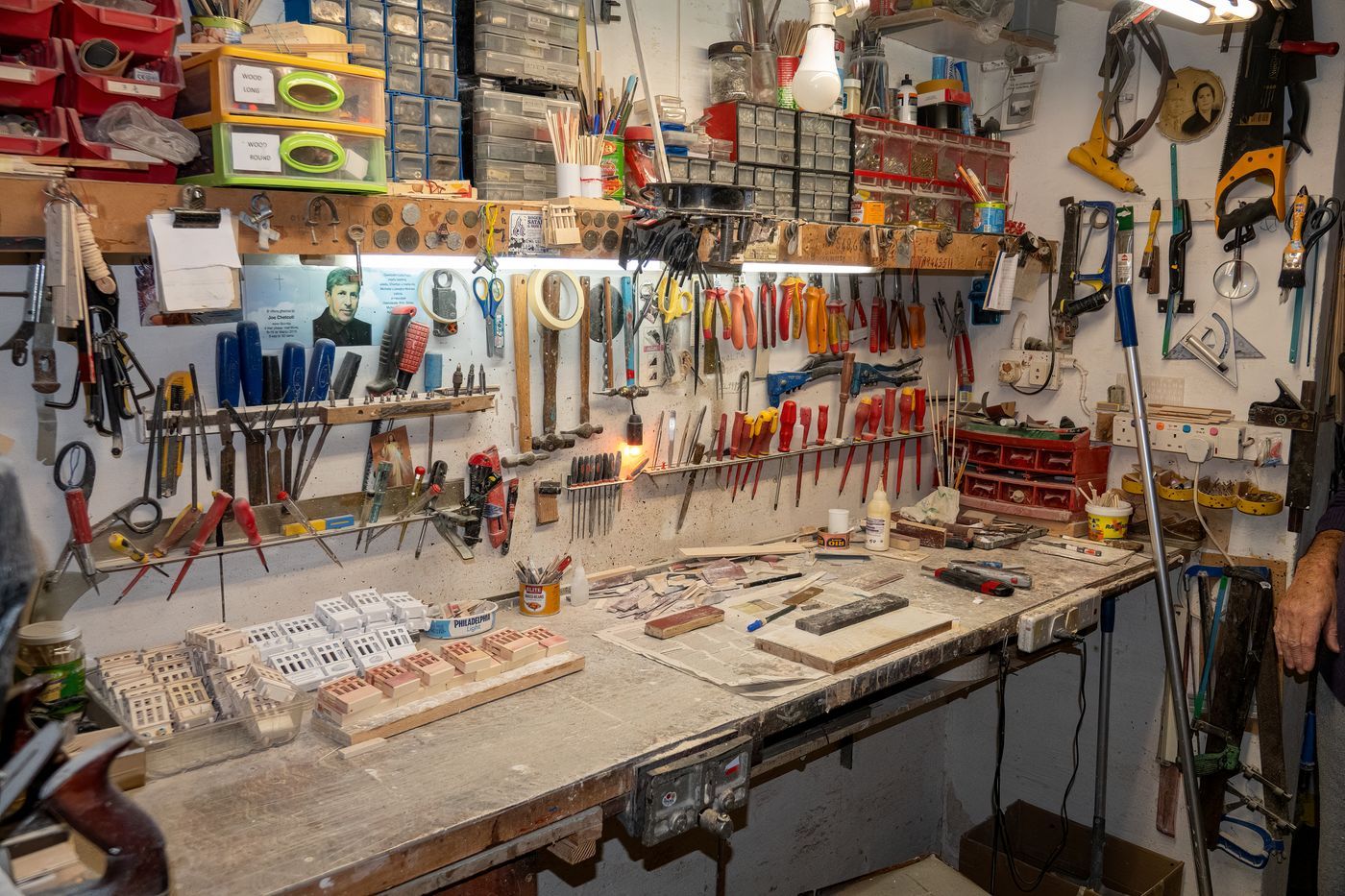 An organized home workshop with hand tools hung on a wall above a workbench