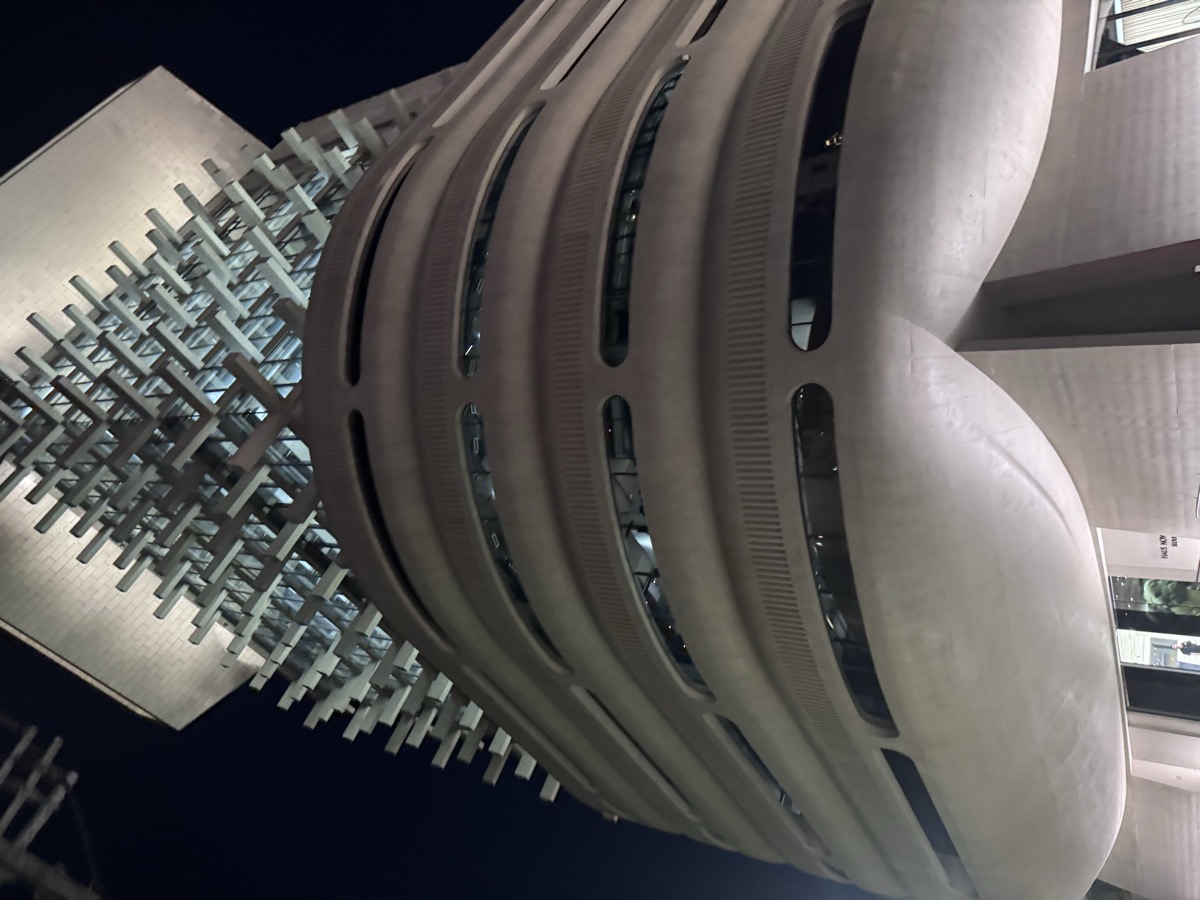Haus Nowhere Seoul, the curved concrete building with a steel lattice crown, photographed at night in Seongsu.
