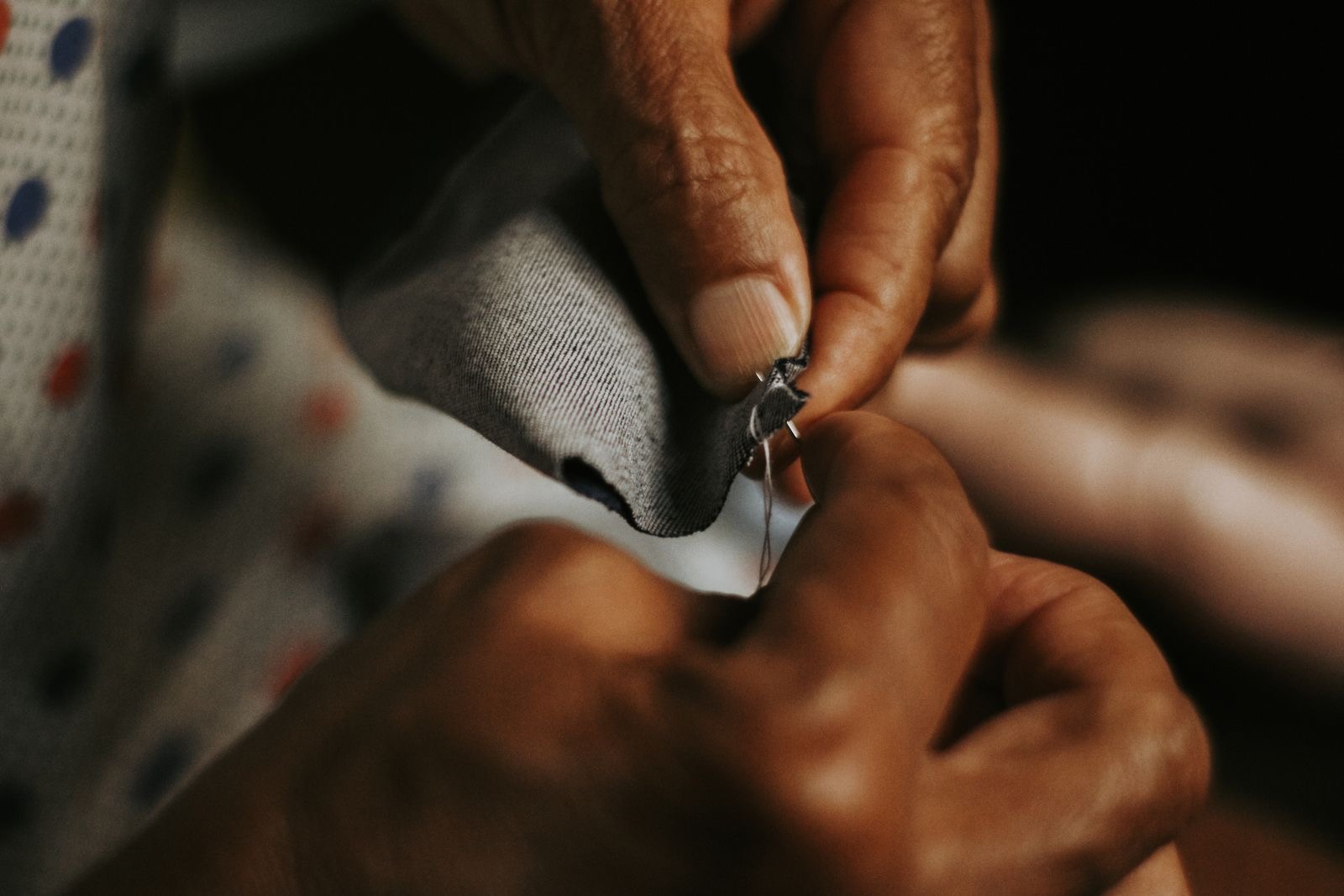 Close-up of hands sewing fabric with a needle and thread.