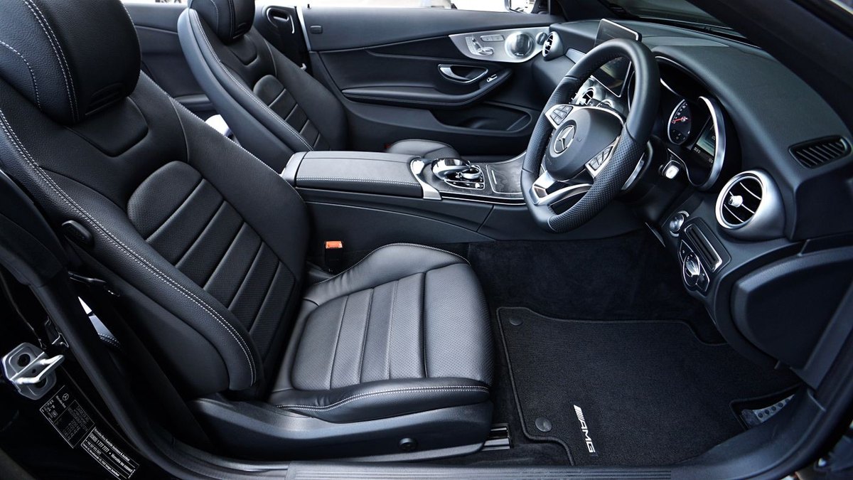 A car interior on the driver's side with rubber floor mats fitted