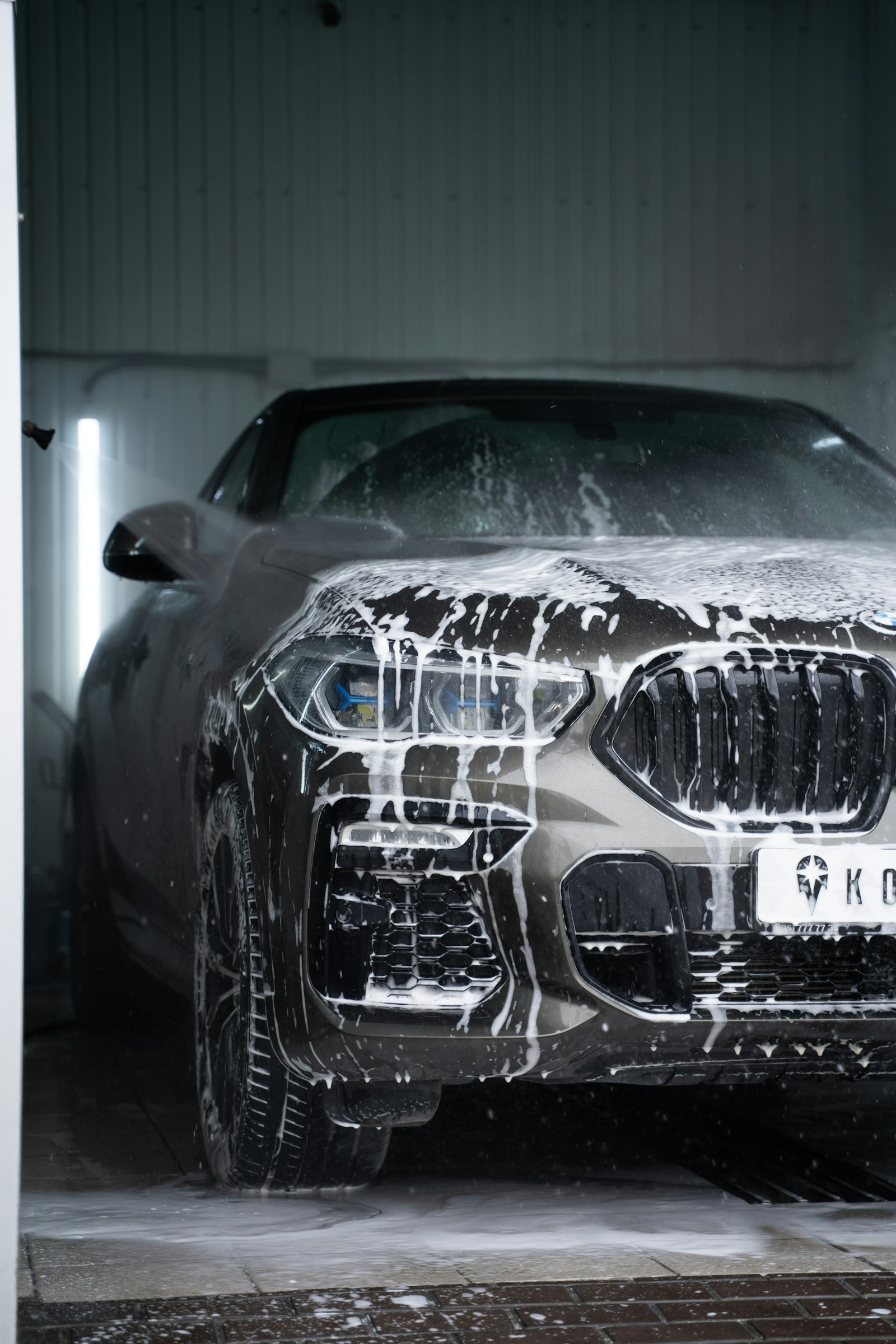 A car covered in white soap suds during a thorough hand wash.