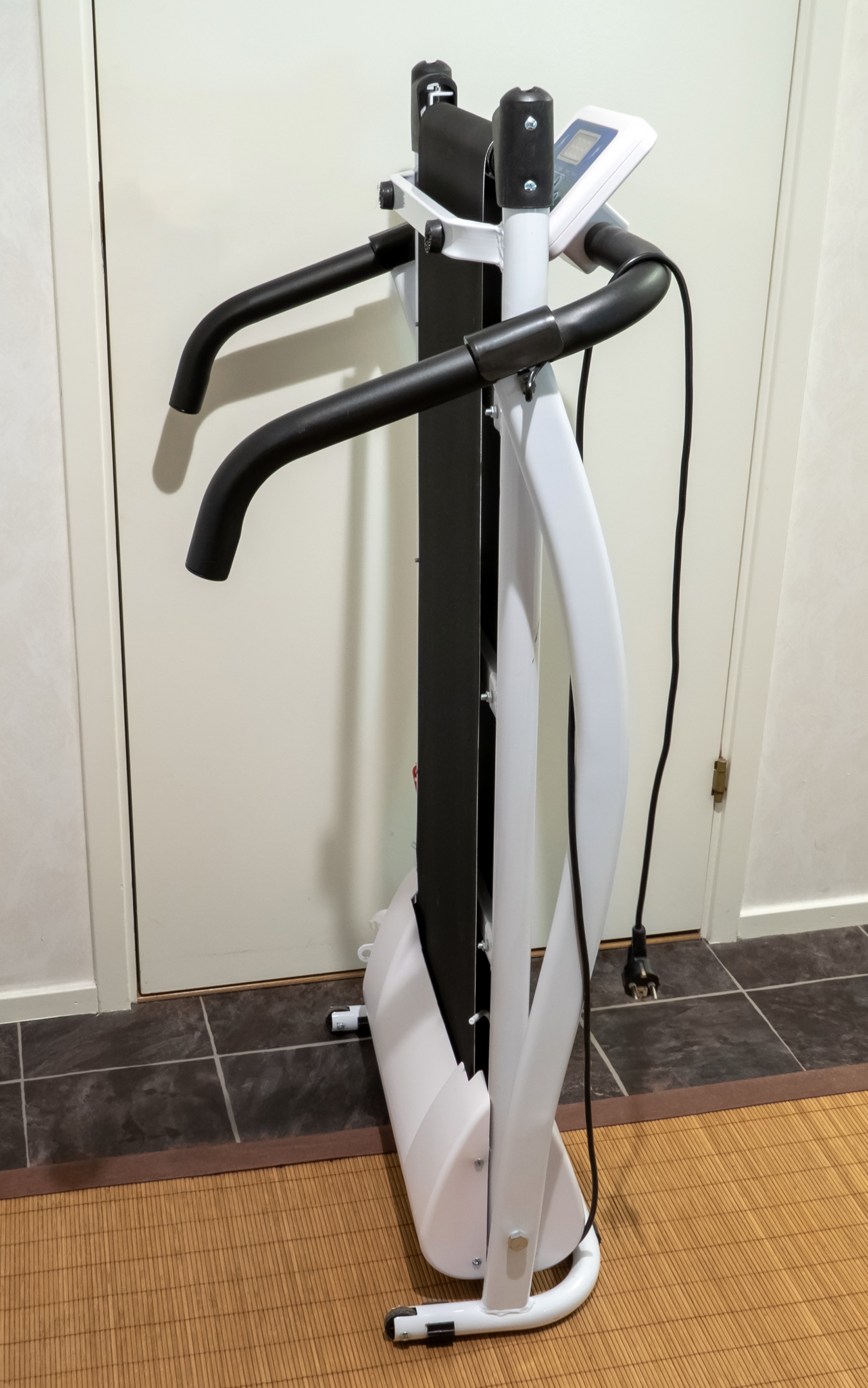 A compact treadmill folded upright against a wall, taking up a narrow footprint.