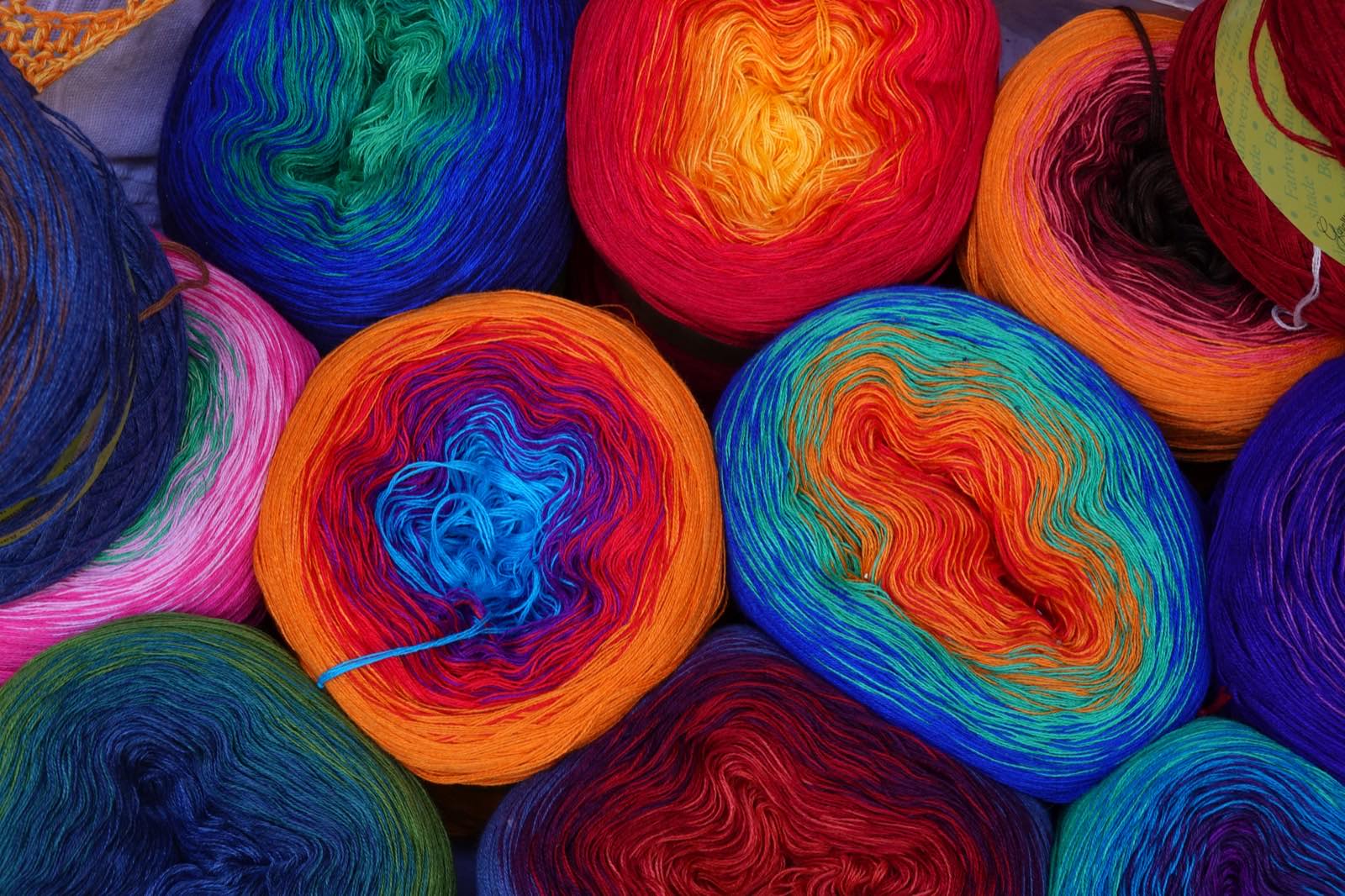 Skeins of brightly colored knitting yarn on display, a real photograph, referencing Cormio's pastel-toned folkloric knitwear.