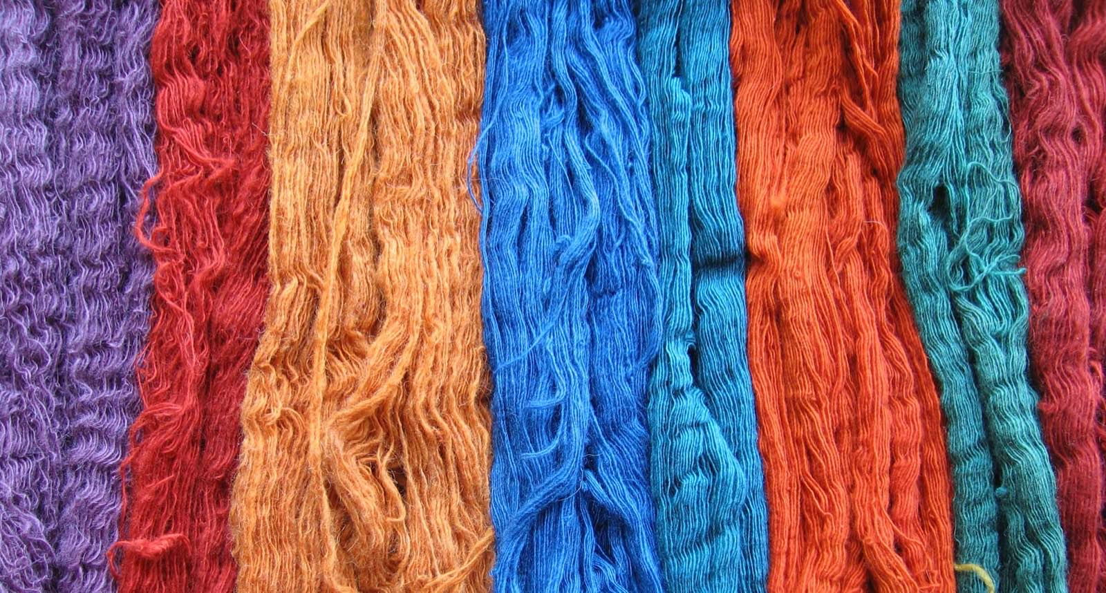 Skeins of wool colored with natural plant dyes including indigo and madder root, a real photograph, referencing Story mfg's naturally-dyed textiles.