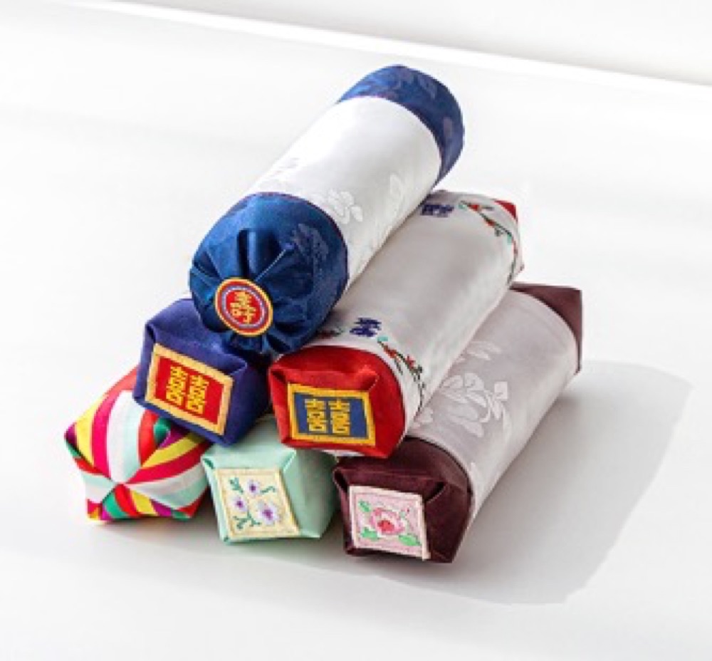 Bojagi-wrapped wrist pillows in traditional Korean silk patterns, real product photo.